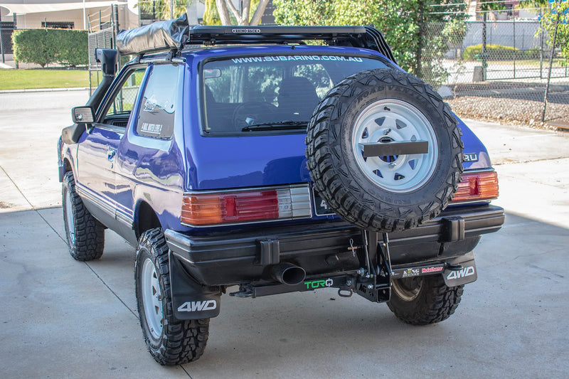 Load image into Gallery viewer, Explore any horizon: Subaru Outback/Forester 4WD ready for adventure with Mirack's tilting spare wheel carrier, tow hitch, & license plate holder.