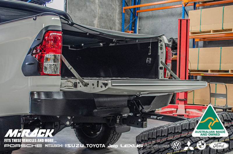 Load image into Gallery viewer, Unlock the full potential of your Toyota Hilux SR5's rear space and off-road capabilities with this rugged Mirack tilting spare tyre carrier, conveniently mounted on the tow hitch. Access the spare tyre effortlessly and keep the rear cargo space clutter-free for your next adventure.